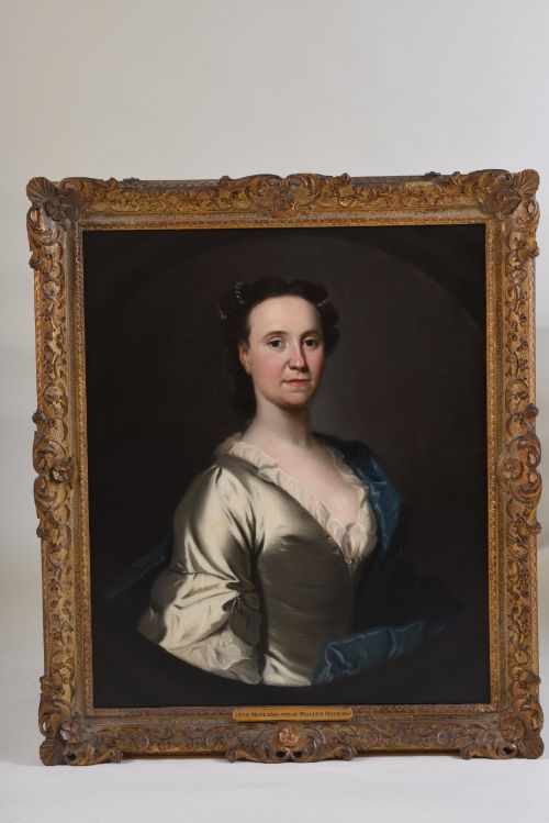fig 1. An 18th-century oil painting on canvas depicting a seated woman in a cream satin dress with a blue wrap, set within an ornate carved giltwood frame.