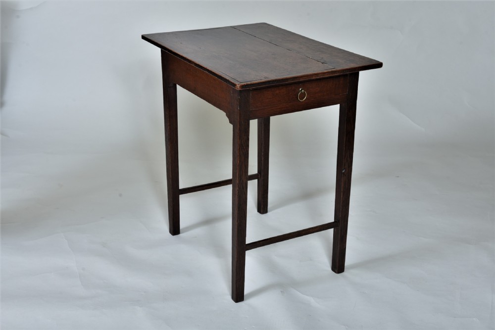 An 18th-century dark oak side table featuring a single frieze drawer with a small brass ring pull, straight square legs, and lower H-stretchers.