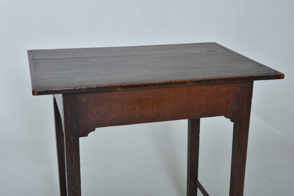 An 18th-century dark oak side table featuring a single frieze drawer with a small brass ring pull, straight square legs, and lower H-stretchers. View V