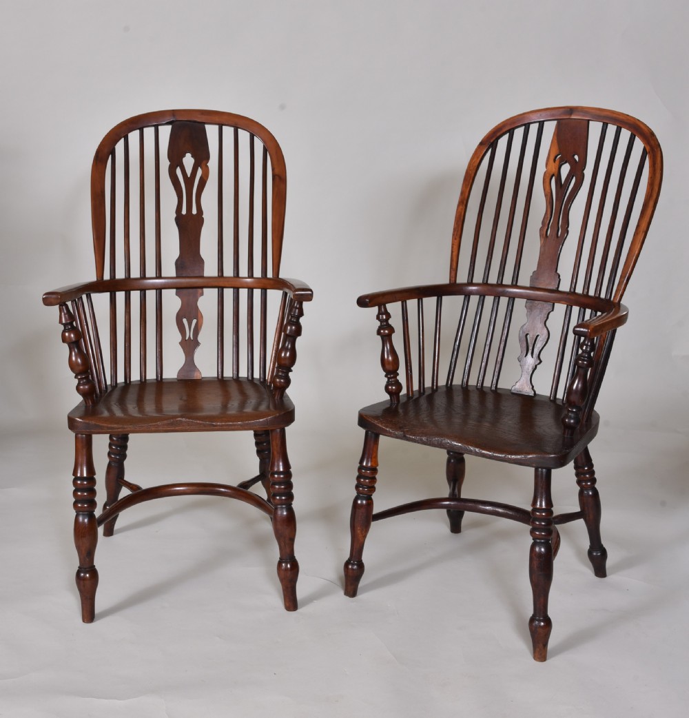 A pair of 19th-century yew wood Windsor armchairs with hoop backs, pierced splats, turned legs, and crinoline stretchers.