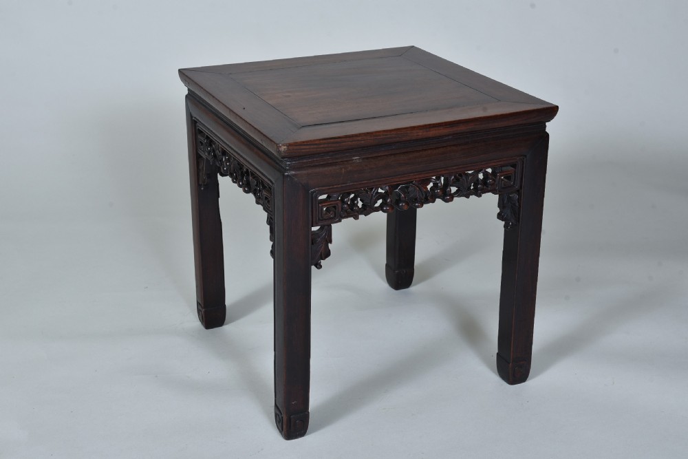 A square dark hardwood Chinese side table featuring carved openwork aprons, decorative spandrels, and straight square legs.
