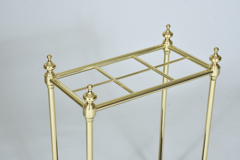 A Victorian brass umbrella stand featuring a six-compartment upper grid, turned finials, upright supports, and a black cast iron drip tray. View II