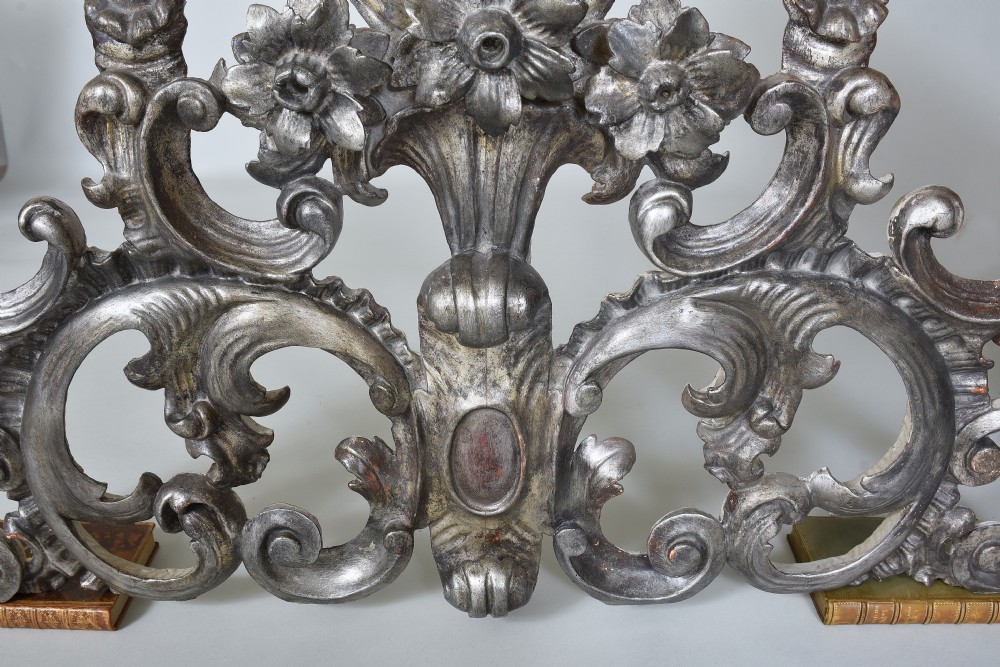 An 18th-century Italian carved wooden pediment finished in aged silver leaf featuring floral motifs, acanthus scrollwork, and raised pedestals. View IV
