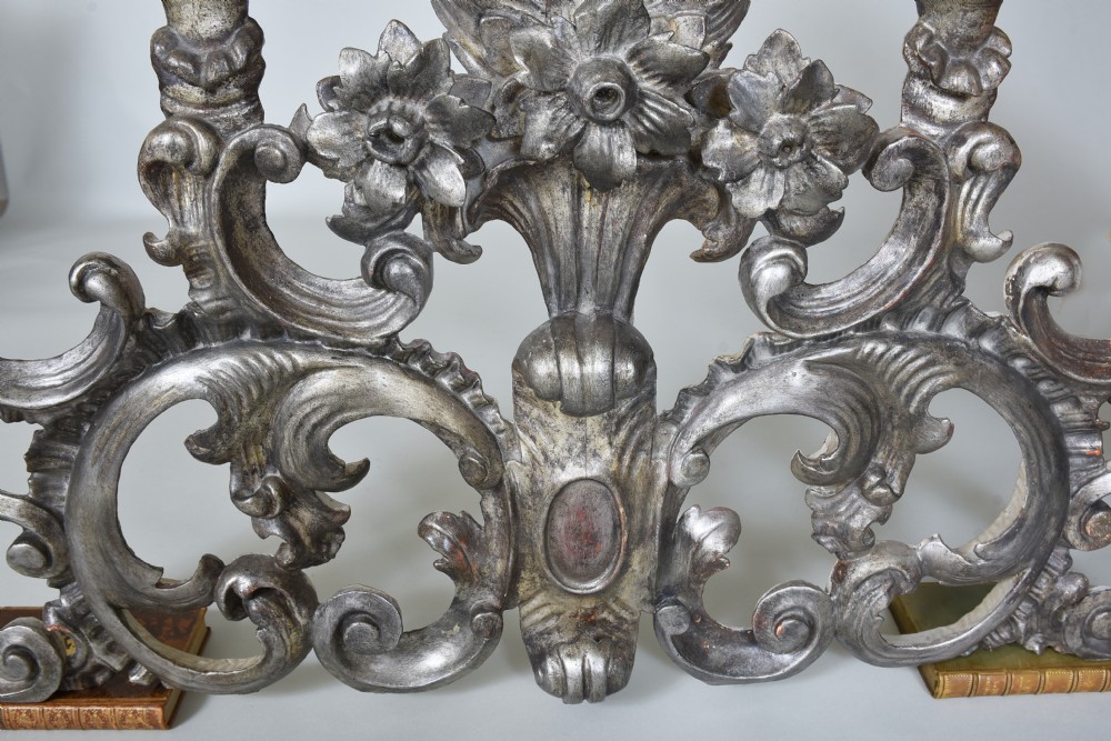 An 18th-century Italian carved wooden pediment finished in aged silver leaf featuring floral motifs, acanthus scrollwork, and raised pedestals. View V