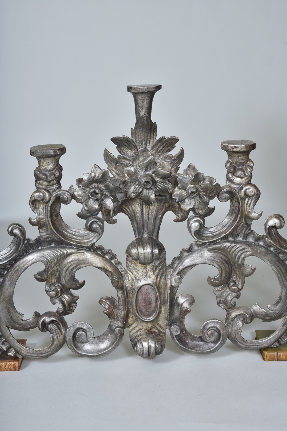 An 18th-century Italian carved wooden pediment finished in aged silver leaf featuring floral motifs, acanthus scrollwork, and raised pedestals. View VI
