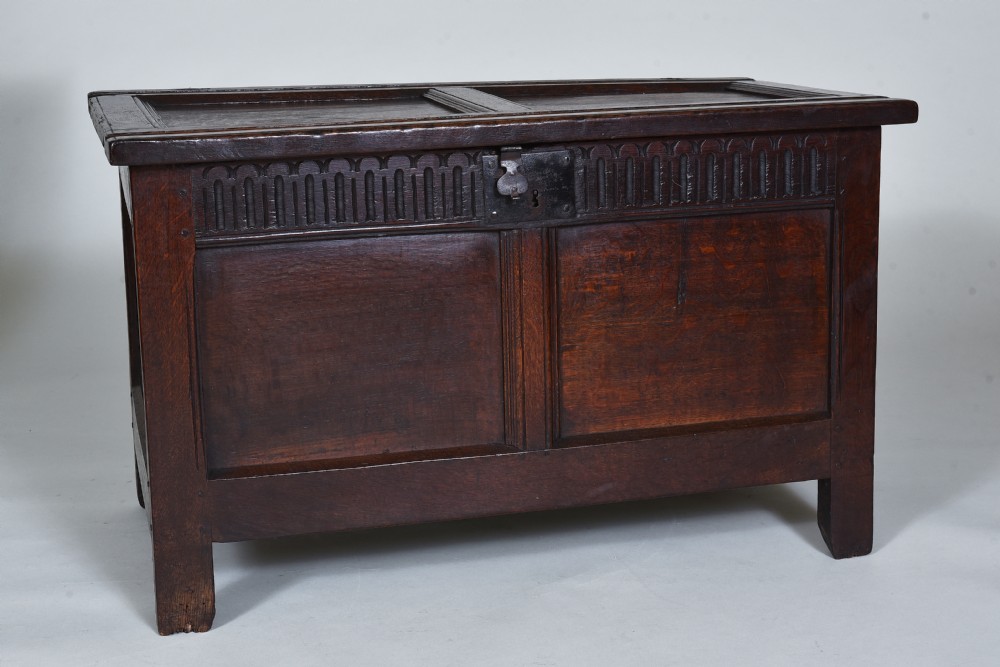 A dark oak 17th-century coffer featuring a carved fluted upper frieze, twin front panels, and a central iron lock plate. View III