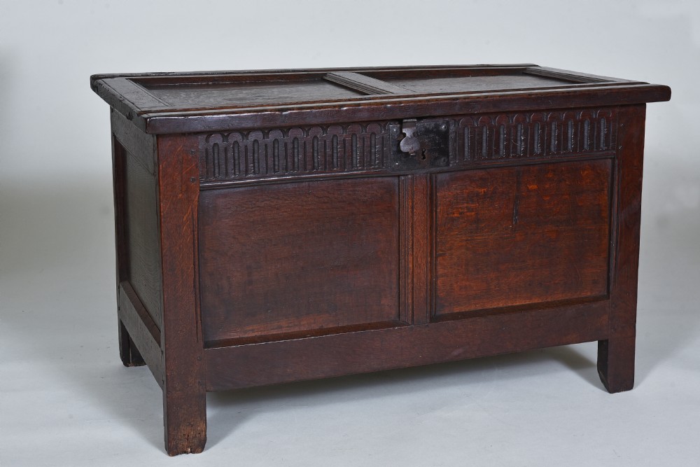 A dark oak 17th-century coffer featuring a carved fluted upper frieze, twin front panels, and a central iron lock plate. View VI