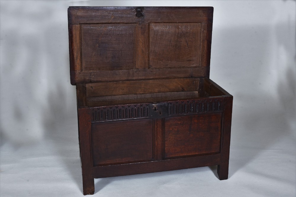 A dark oak 17th-century coffer featuring a carved fluted upper frieze, twin front panels, and a central iron lock plate. View VIII
