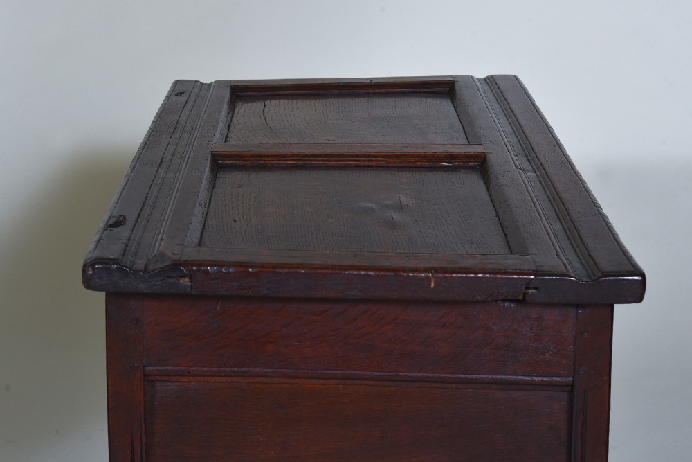A dark oak 17th-century coffer featuring a carved fluted upper frieze, twin front panels, and a central iron lock plate. View X