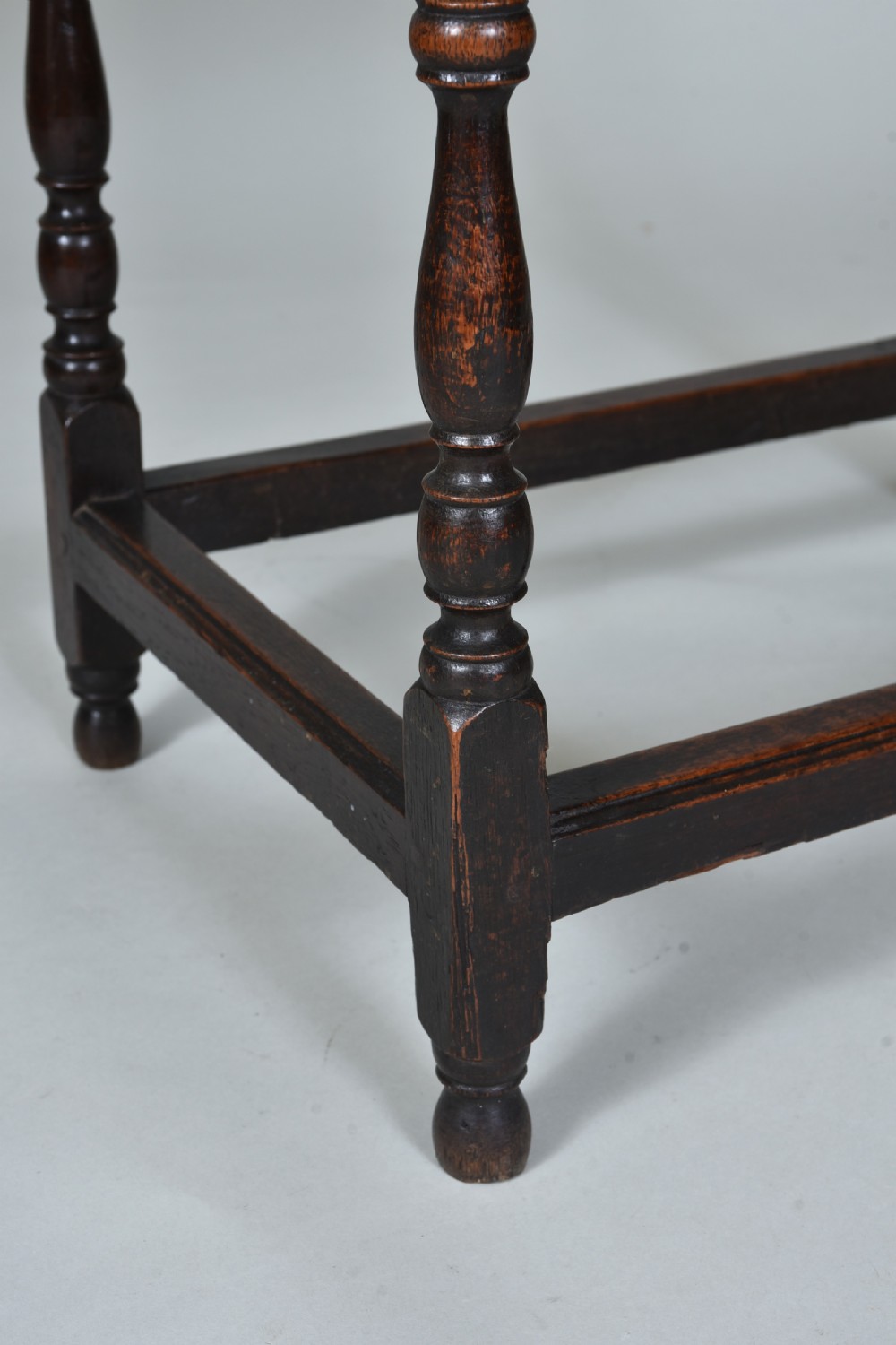 A 17th century dark oak side table featuring a single drawer with brass drop handles, turned legs, and a low box stretcher. View VI