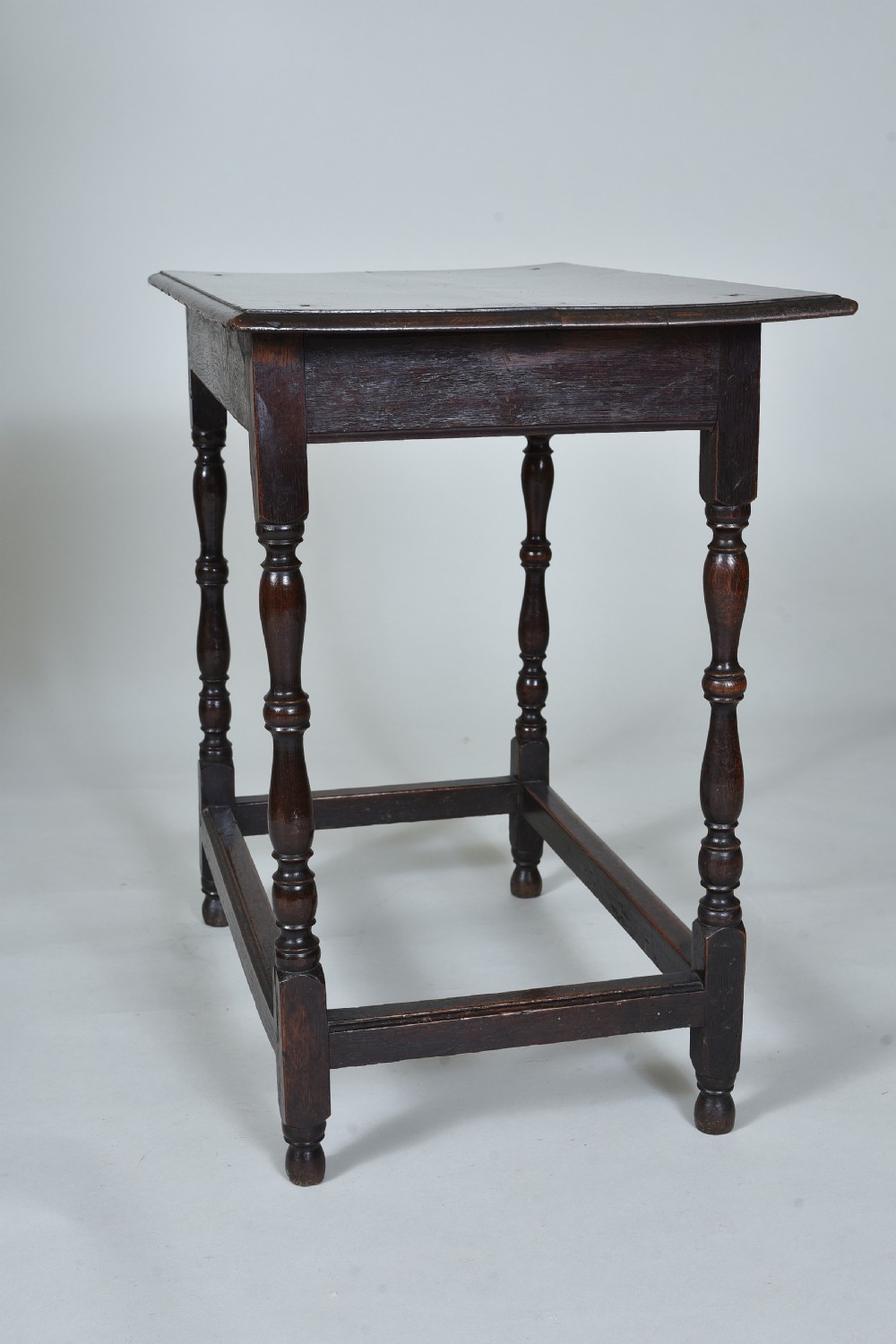 A 17th century dark oak side table featuring a single drawer with brass drop handles, turned legs, and a low box stretcher. View VII