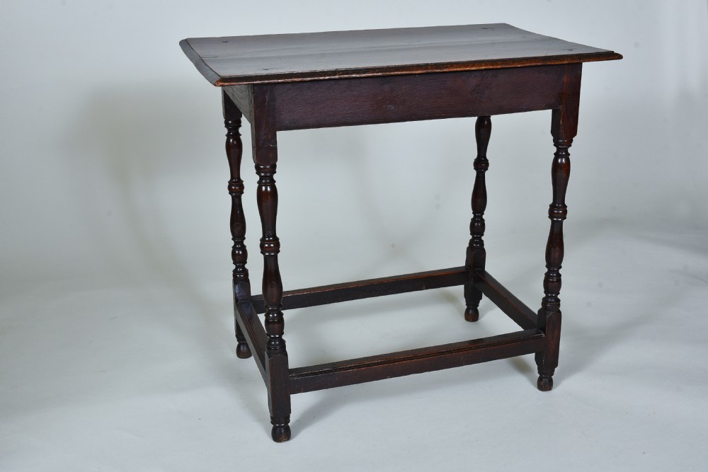 A 17th century dark oak side table featuring a single drawer with brass drop handles, turned legs, and a low box stretcher. View VIII