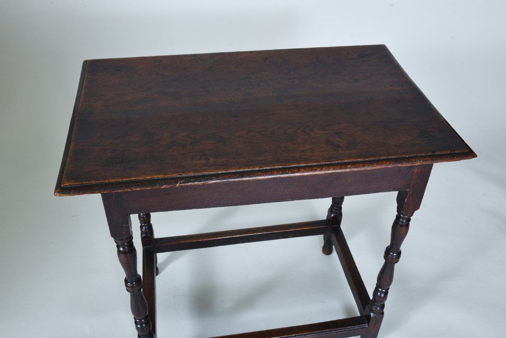 A 17th century dark oak side table featuring a single drawer with brass drop handles, turned legs, and a low box stretcher. View IX