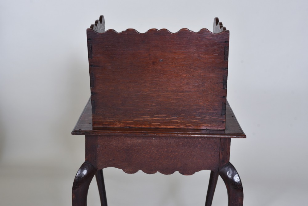 An 18th-century dark oak side table featuring curved cabriole legs, a scalloped apron, and a raised two-tier scalloped gallery shelf. View VI