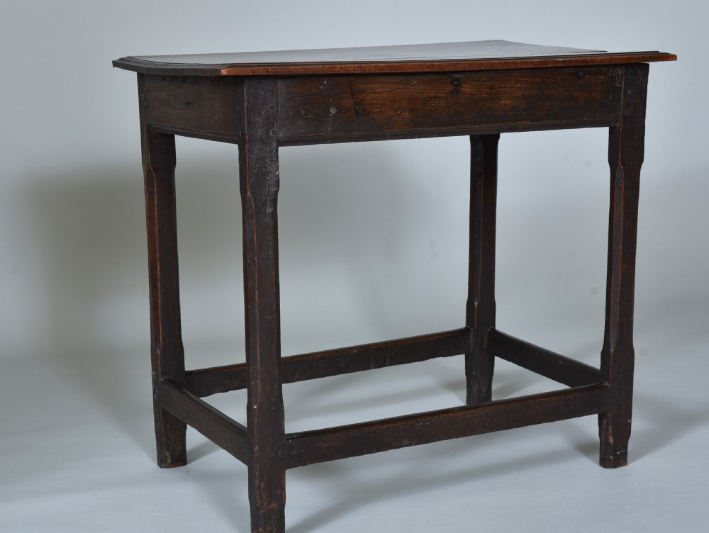 An early eighteenth-century dark oak side table with square chamfered legs, lower box stretchers, and a flat rectangular top.