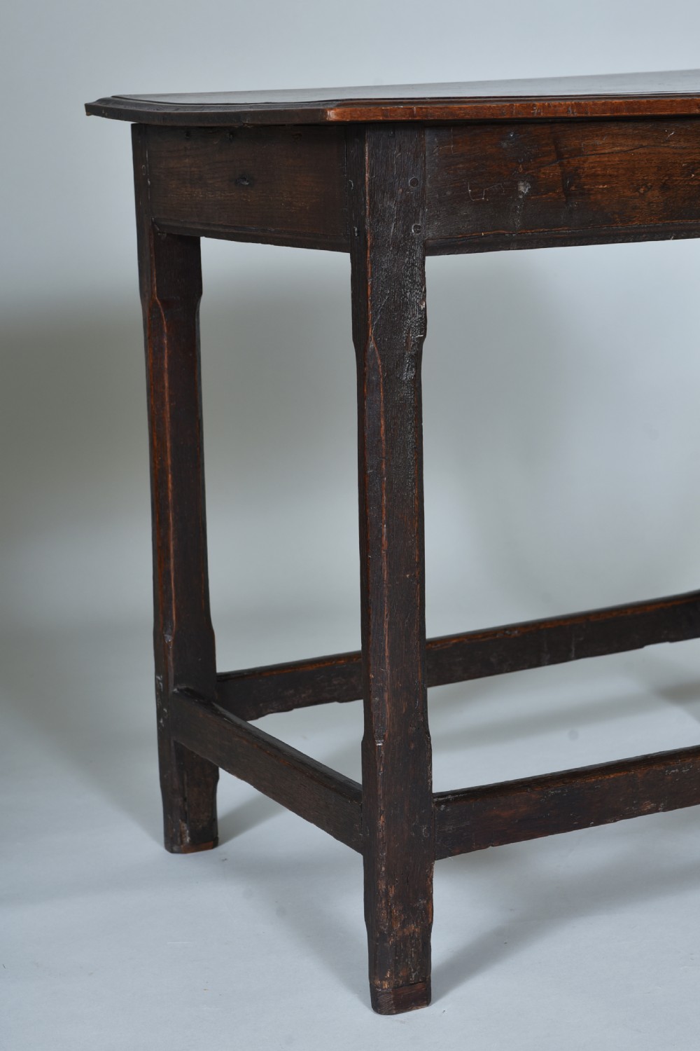 An early eighteenth-century dark oak side table with square chamfered legs, lower box stretchers, and a flat rectangular top. View III