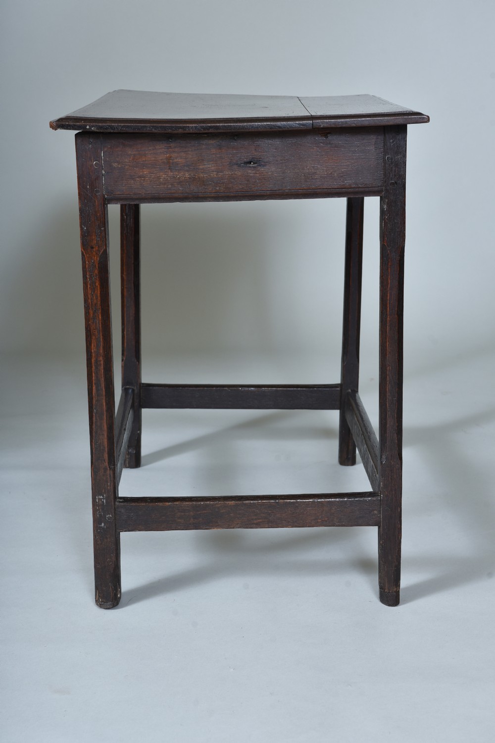 An early eighteenth-century dark oak side table with square chamfered legs, lower box stretchers, and a flat rectangular top. View V