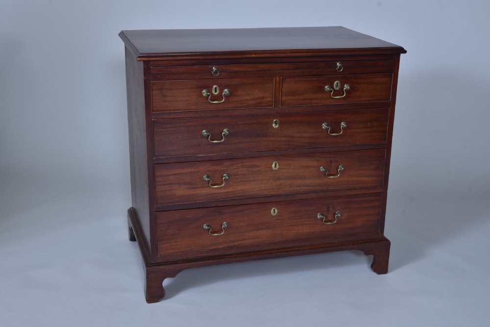 A Georgian mahogany chest of drawers featuring a pull-out brushing slide, two short drawers over three long graduated drawers, brass drop handles, and bracket feet.