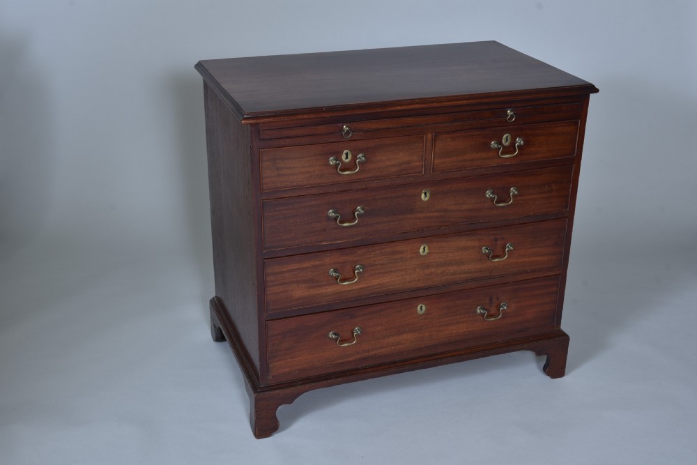A Georgian mahogany chest of drawers featuring a pull-out brushing slide, two short drawers over three long graduated drawers, brass drop handles, and bracket feet. View II
