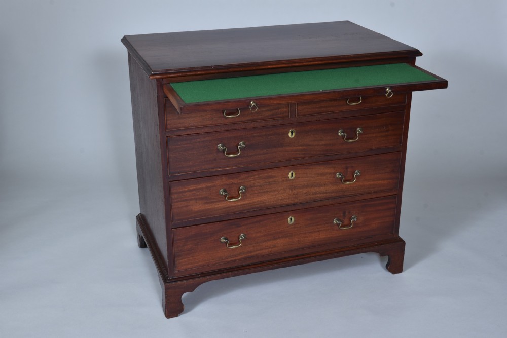 A Georgian mahogany chest of drawers featuring a pull-out brushing slide, two short drawers over three long graduated drawers, brass drop handles, and bracket feet. View III