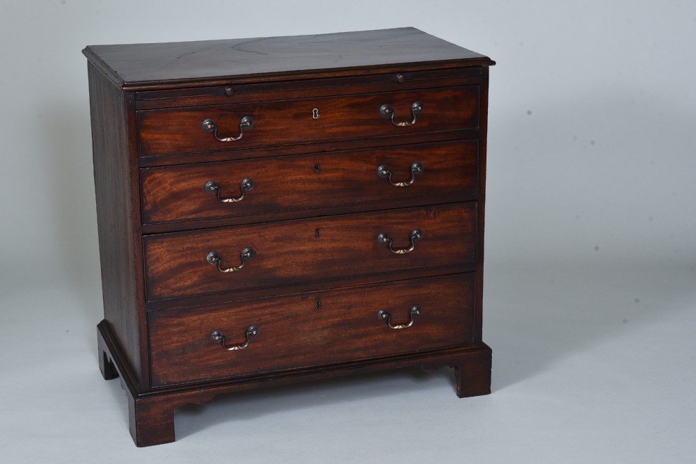 A Georgian mahogany chest of drawers featuring four graduated long drawers with brass swan-neck handles, a pull-out brushing slide, and bracket feet.