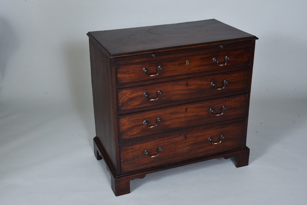 A Georgian mahogany chest of drawers featuring four graduated long drawers with brass swan-neck handles, a pull-out brushing slide, and bracket feet. View II
