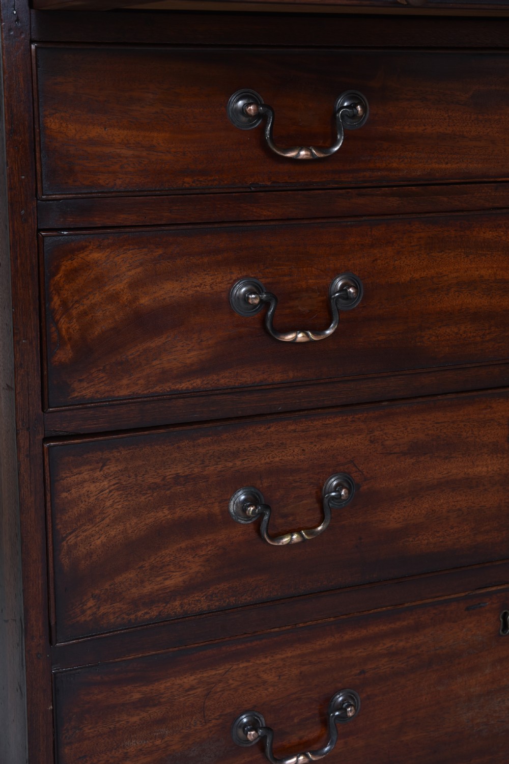 A Georgian mahogany chest of drawers featuring four graduated long drawers with brass swan-neck handles, a pull-out brushing slide, and bracket feet. View VI