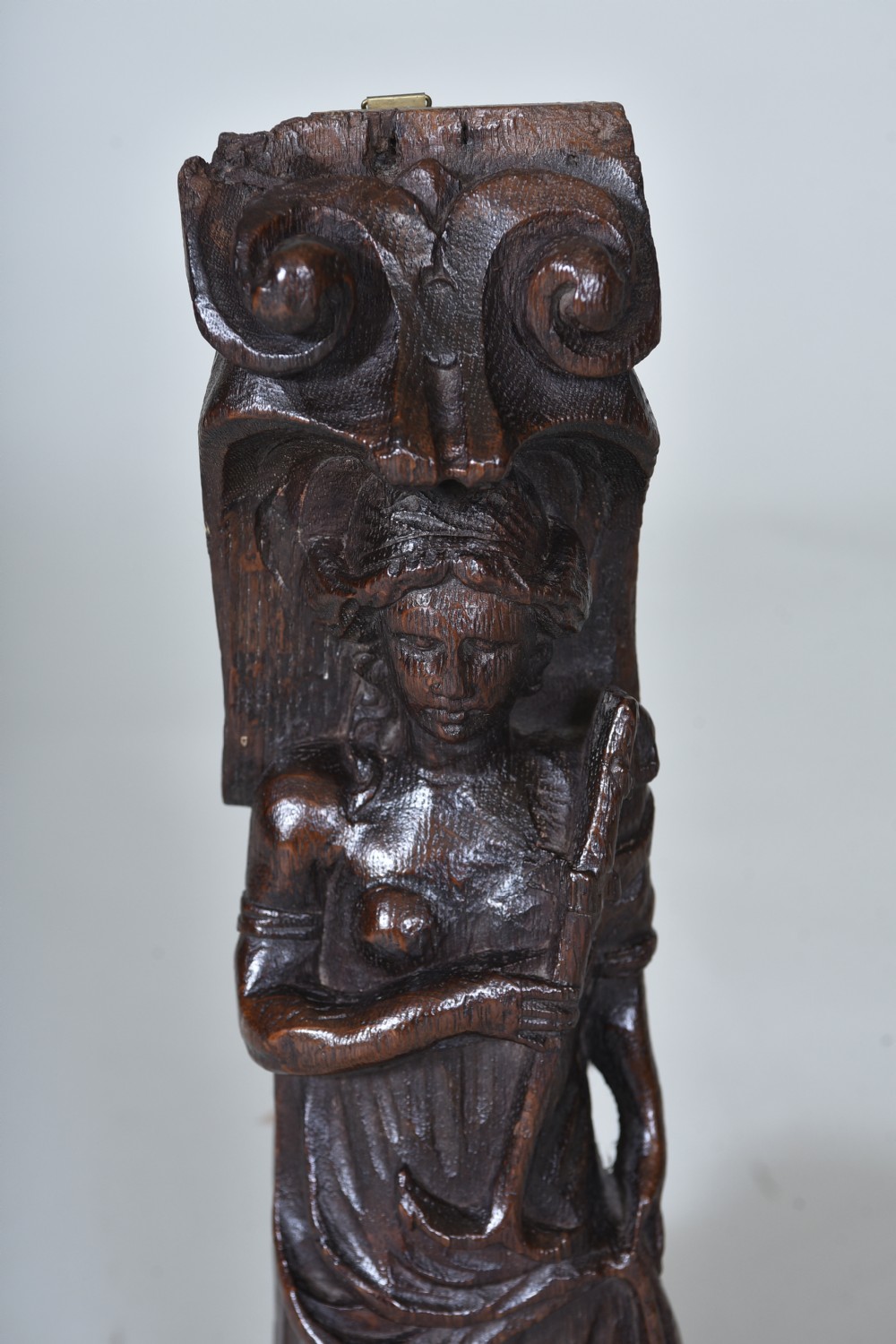 A dark carved oak 17th-century architectural fragment featuring a relief female figure with an anchor topped with ionic scrollwork. View II