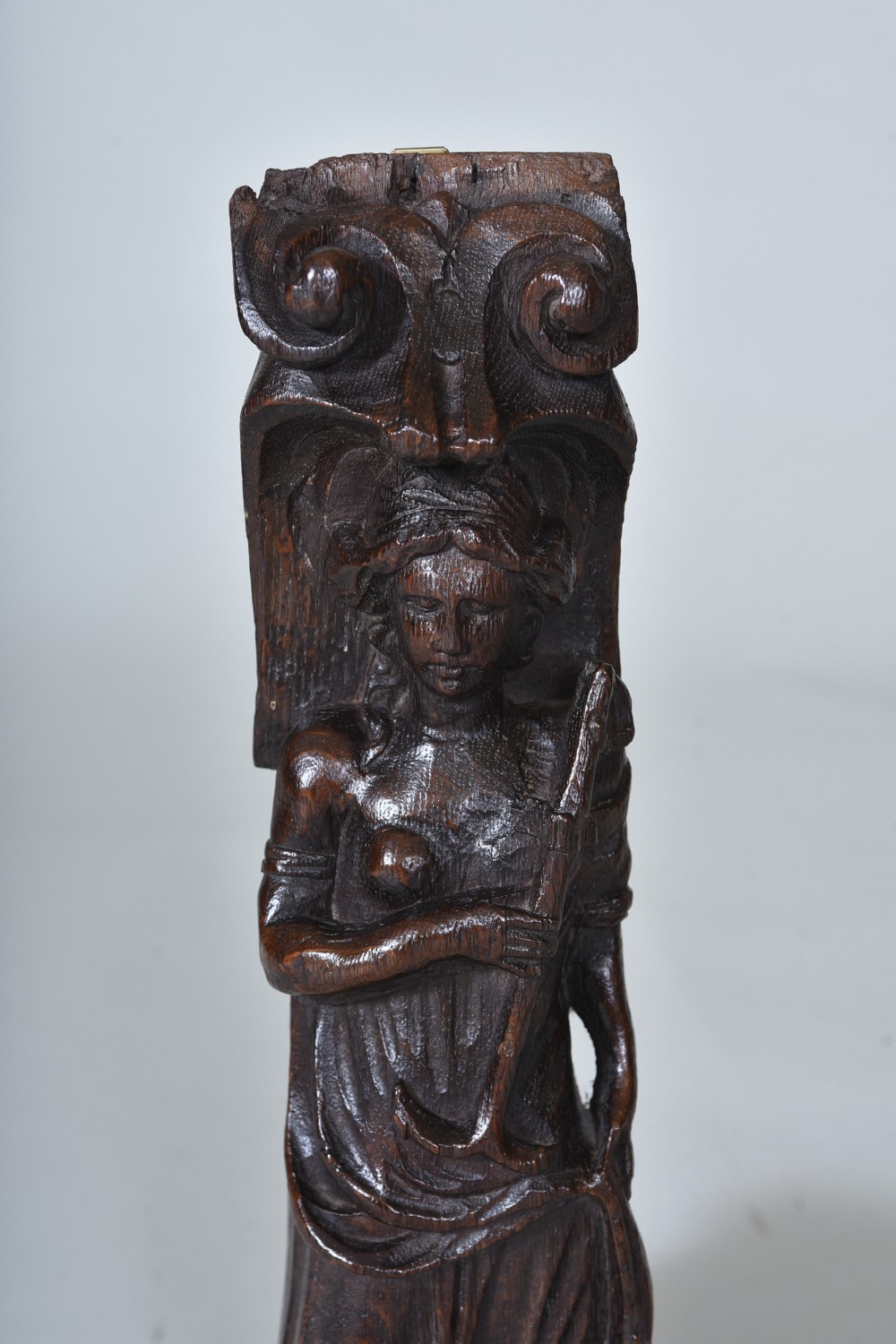 A dark carved oak 17th-century architectural fragment featuring a relief female figure with an anchor topped with ionic scrollwork. View III