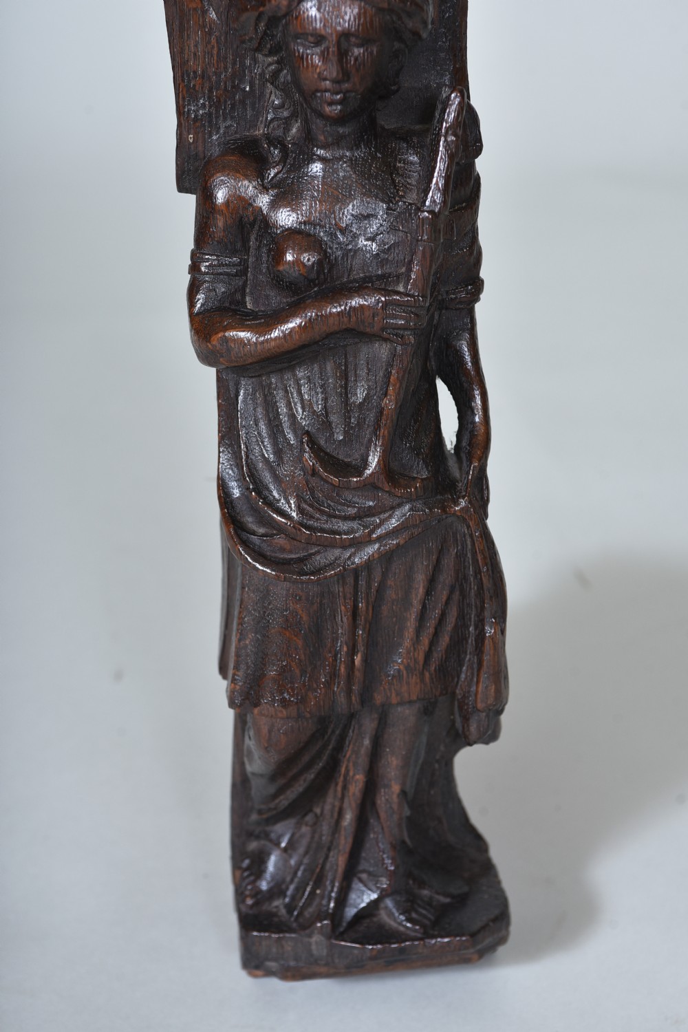 A dark carved oak 17th-century architectural fragment featuring a relief female figure with an anchor topped with ionic scrollwork. View IV