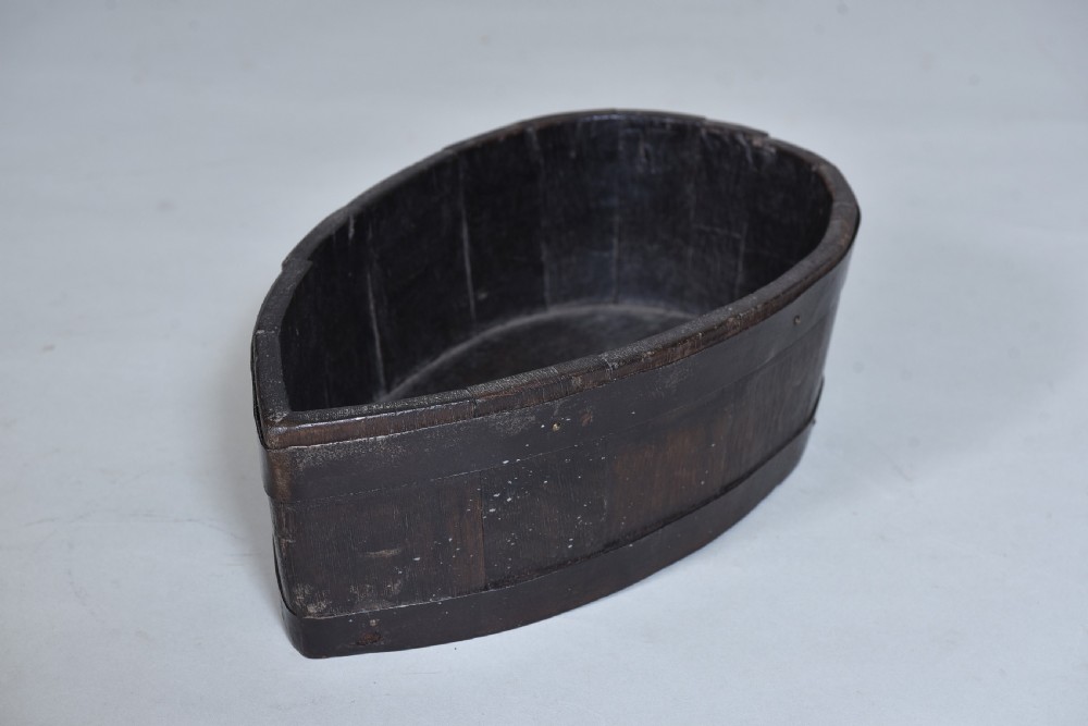 A dark brown teardrop-shaped antique wooden treen vessel bound with iron hoops.