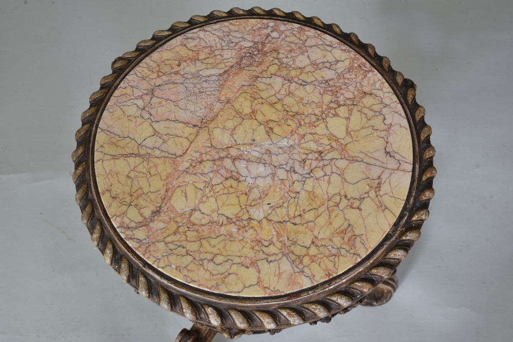 A 19th-century circular side table featuring a mottled marble top, intricate carved giltwood apron, and a scrolled tripod support base. View VI