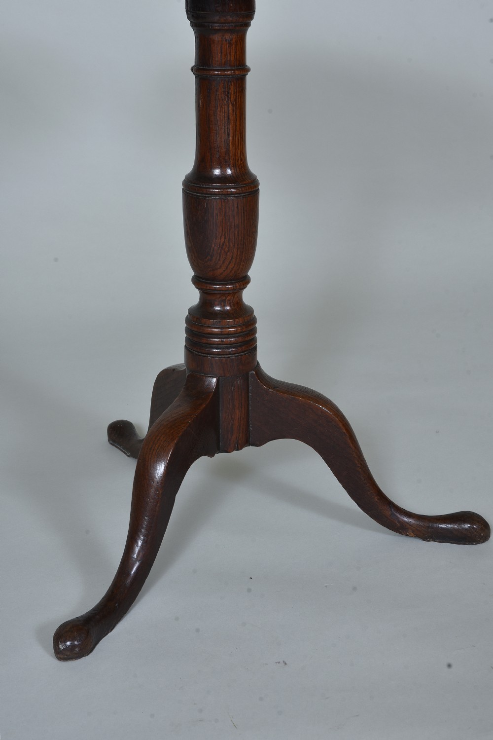 An antique dark oak tripod table with a circular tilt-top resting vertically on a turned central pedestal with three splayed legs. View II