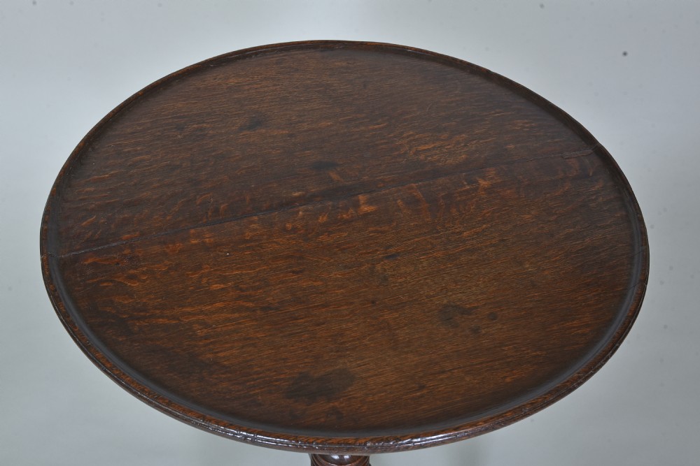 An antique dark oak tripod table with a circular tilt-top resting vertically on a turned central pedestal with three splayed legs. View III