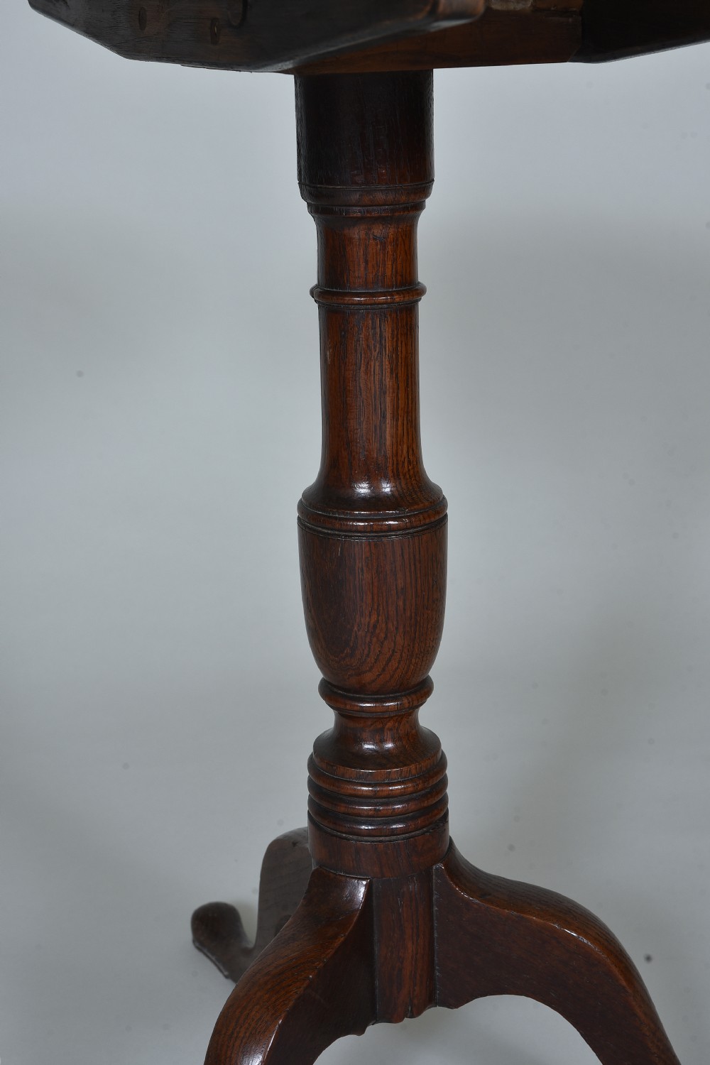 An antique dark oak tripod table with a circular tilt-top resting vertically on a turned central pedestal with three splayed legs. View IV