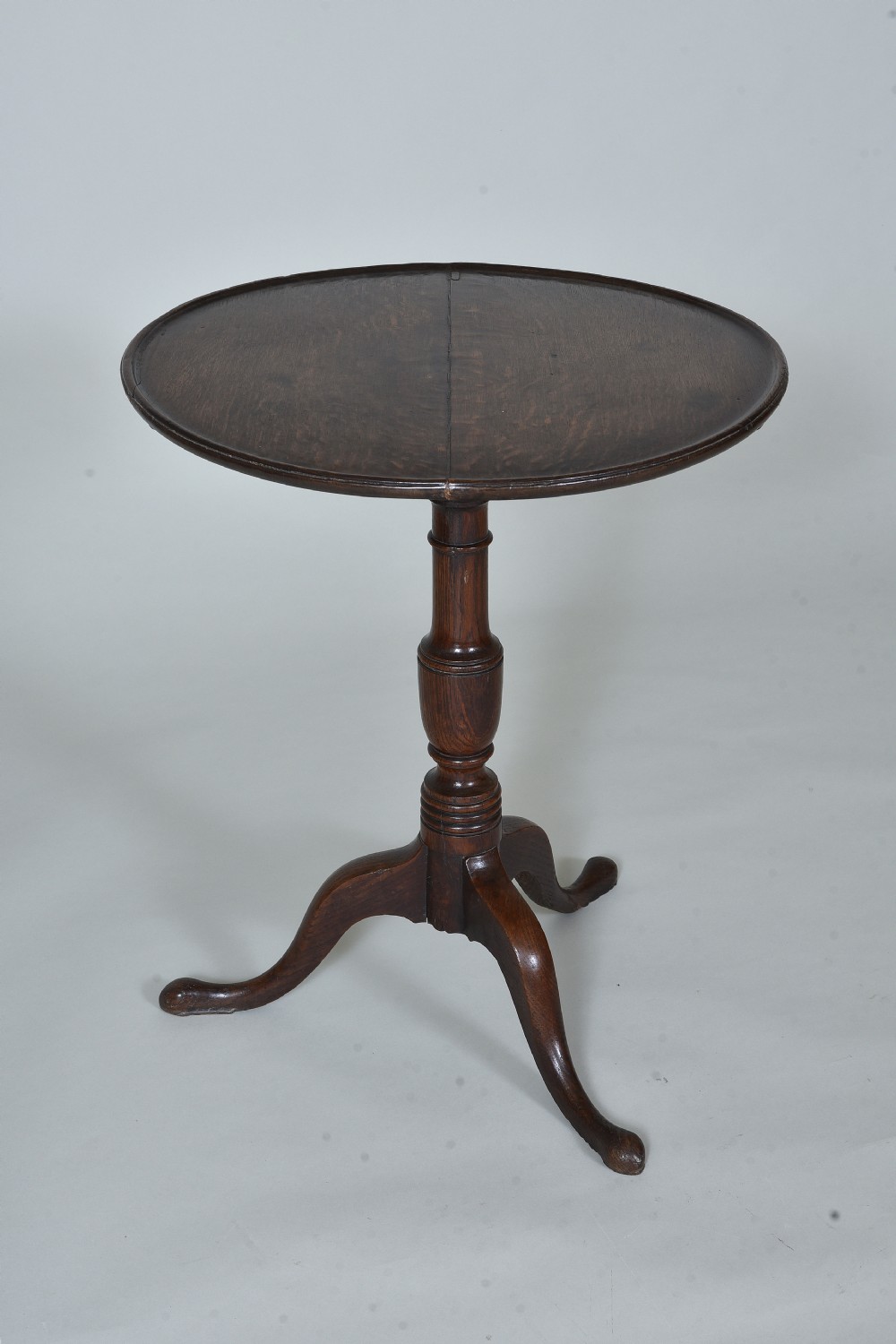 An antique dark oak tripod table with a circular tilt-top resting vertically on a turned central pedestal with three splayed legs. View V
