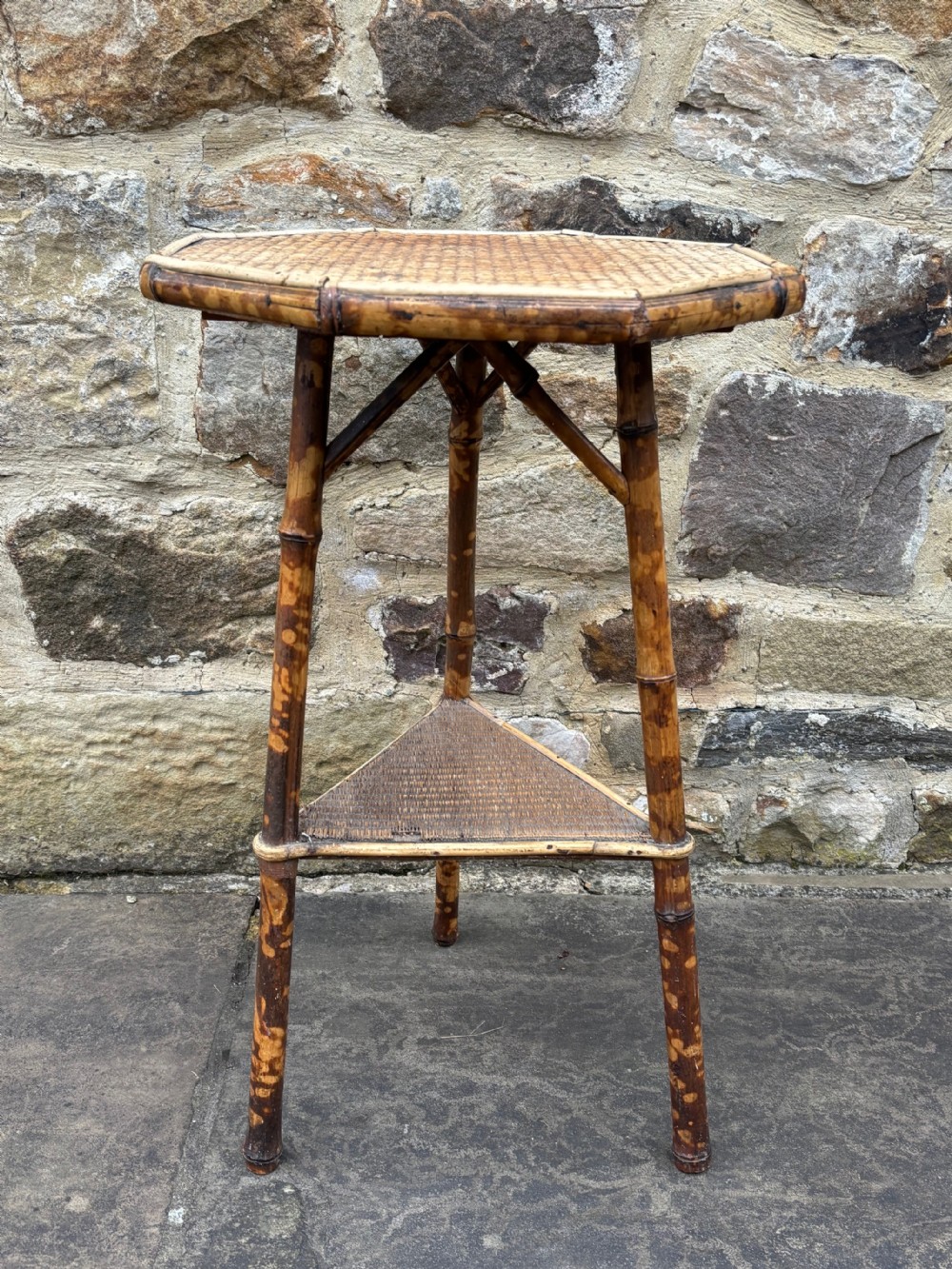 A pair of antique bamboo side tables featuring octagonal woven cane tops, triangular undertiers, and mottled brown bamboo legs. View II