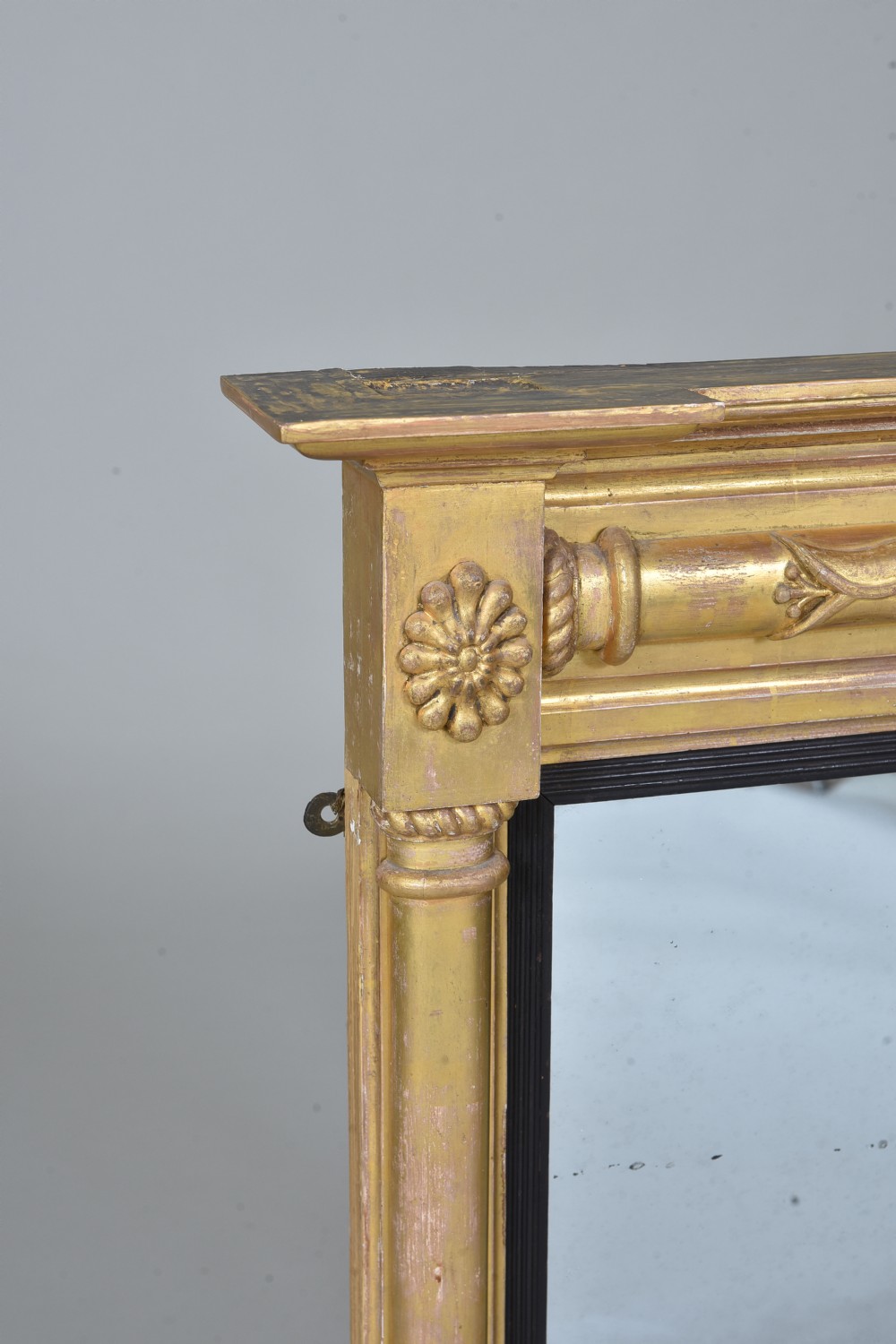 A rectangular Regency giltwood wall mirror featuring side columns, rosette medallions, an ornamental frieze, and an ebonised inner slip. View III