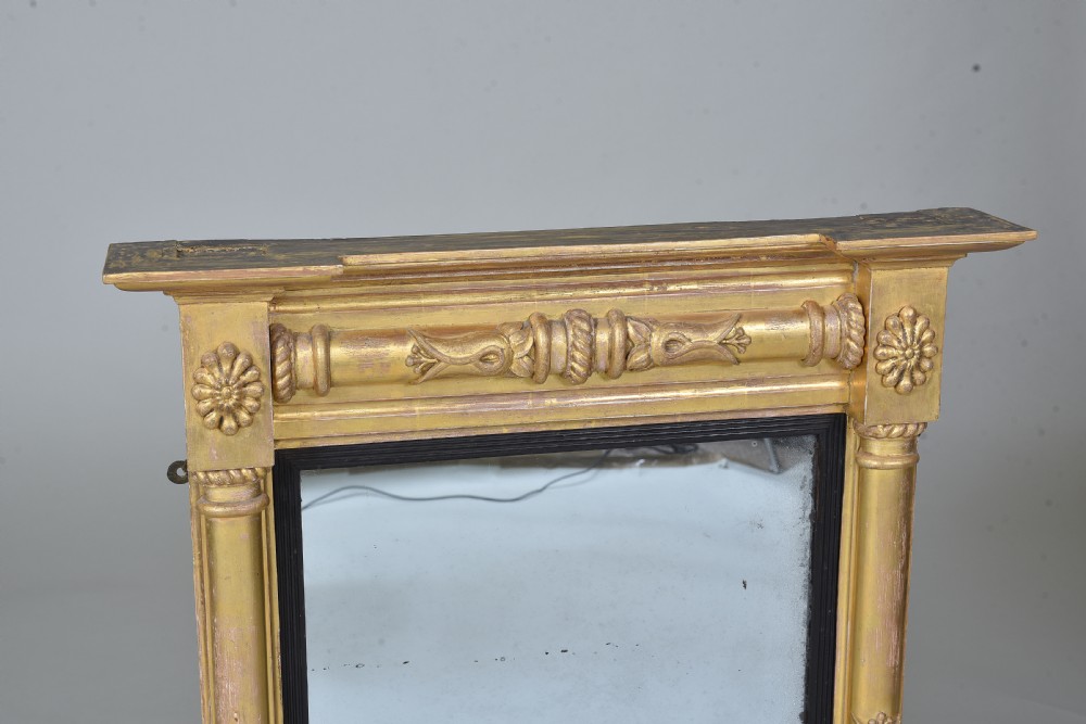 A rectangular Regency giltwood wall mirror featuring side columns, rosette medallions, an ornamental frieze, and an ebonised inner slip. View IV