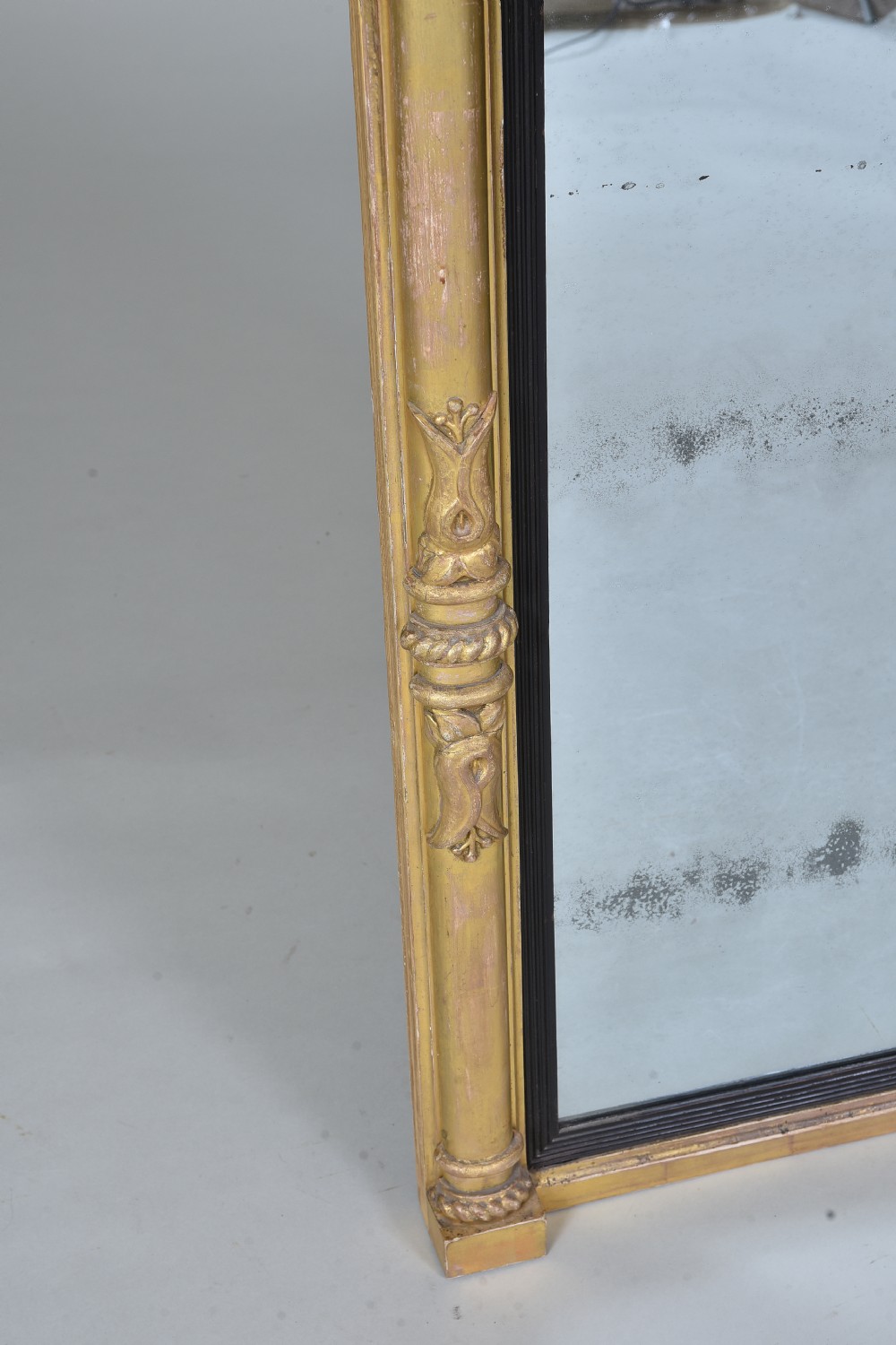 A rectangular Regency giltwood wall mirror featuring side columns, rosette medallions, an ornamental frieze, and an ebonised inner slip. View V