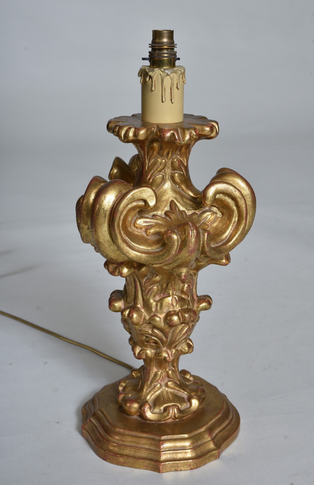 An antique carved giltwood table lamp base featuring scrollwork, acanthus leaf motifs, and a cream faux-candle fitting at the top. View II