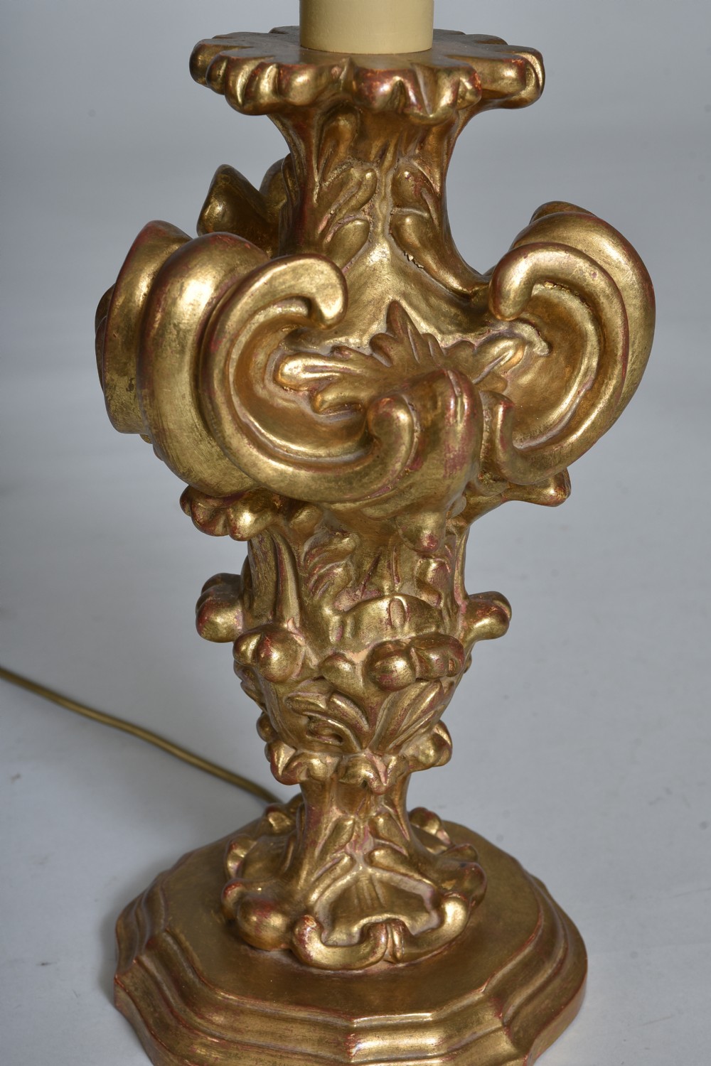 An antique carved giltwood table lamp base featuring scrollwork, acanthus leaf motifs, and a cream faux-candle fitting at the top. View III