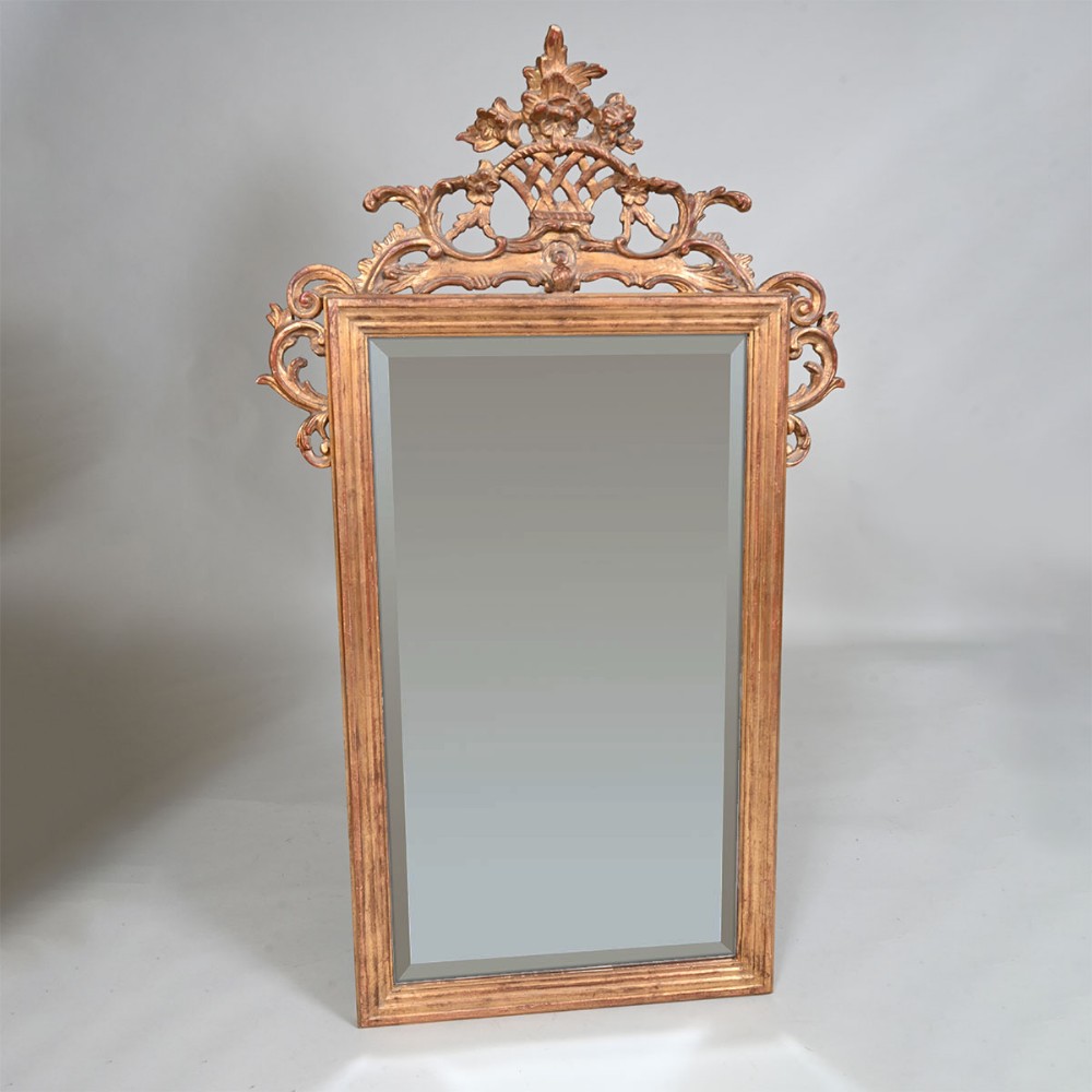 An early 19th-century rectangular giltwood wall mirror featuring a bevelled glass plate topped with openwork lattice and scrollwork cresting.