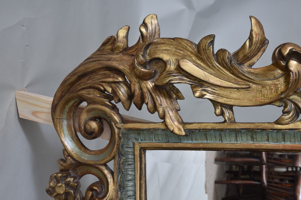 An ornate rectangular wall mirror featuring an elaborate carved giltwood frame decorated with shell motifs, acanthus leaf flourishes, and subtle teal painted accents. View II