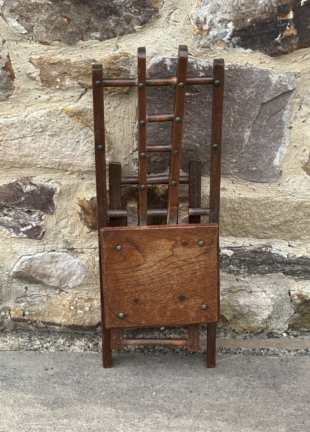 A dark brown wooden folding childs chair featuring an X-frame construction, a flat rectangular seat, and a slatted backrest with metal fixings. View II
