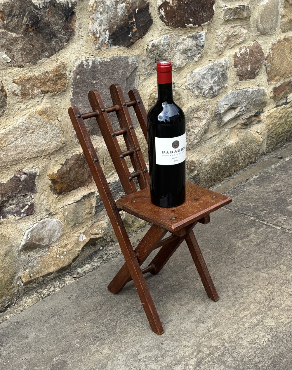 A dark brown wooden folding childs chair featuring an X-frame construction, a flat rectangular seat, and a slatted backrest with metal fixings. View IV