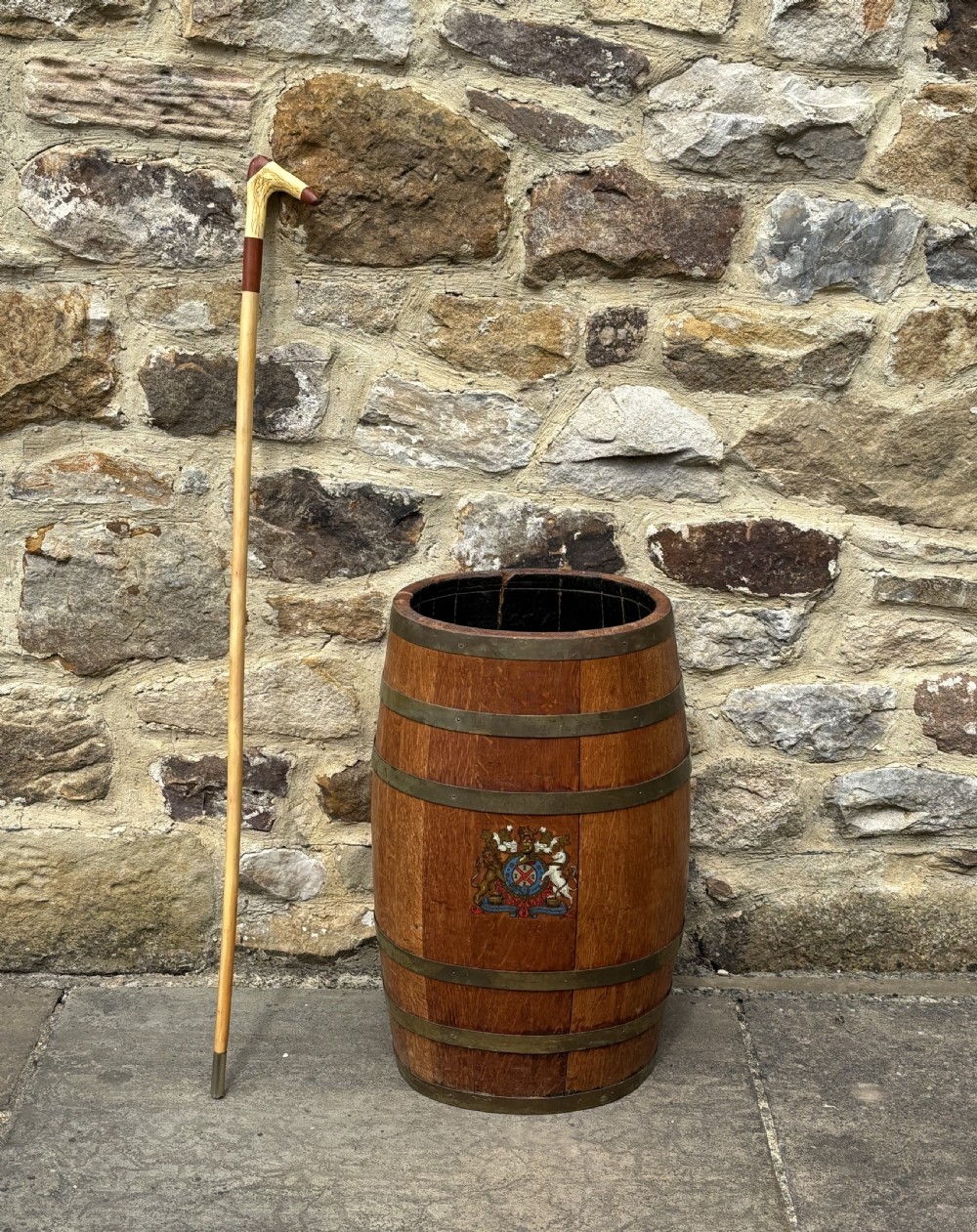 A 19th-century coopered oak barrel stick stand featuring brass hoops and a hand-painted crest on the front.