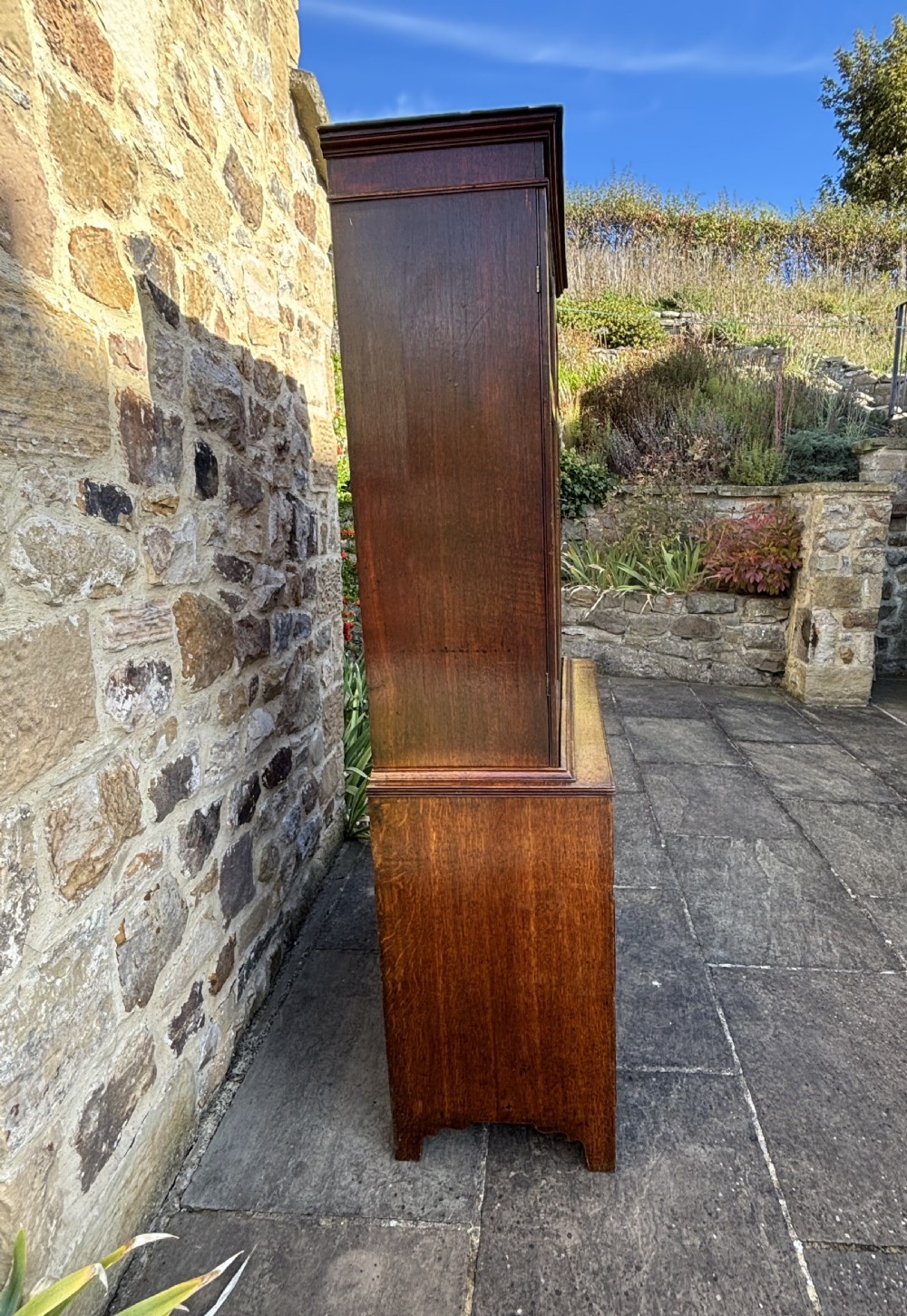 An 18th-century dark oak cupboard on chest featuring paneled upper doors, lower drawers with brass handles, and a moulded cornice. View VIII