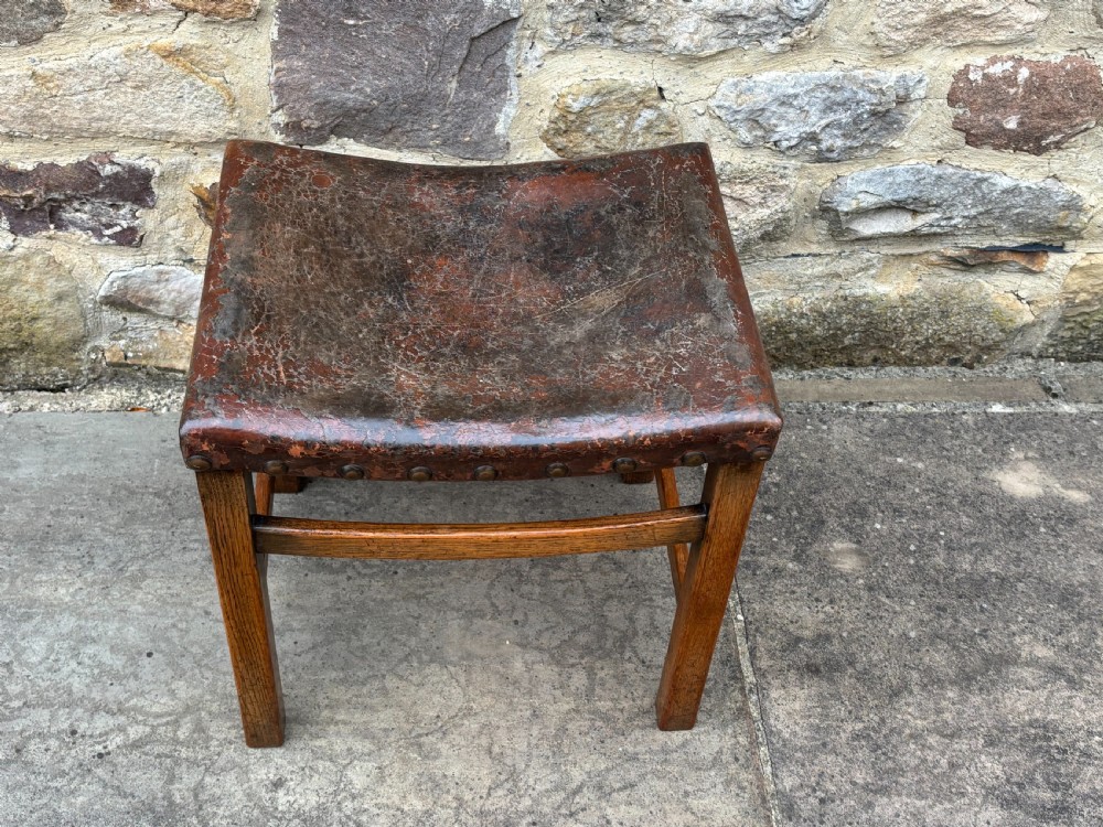 An Edwardian stool constructed from dark oak featuring a curved leather saddle seat secured with metal studs. View III