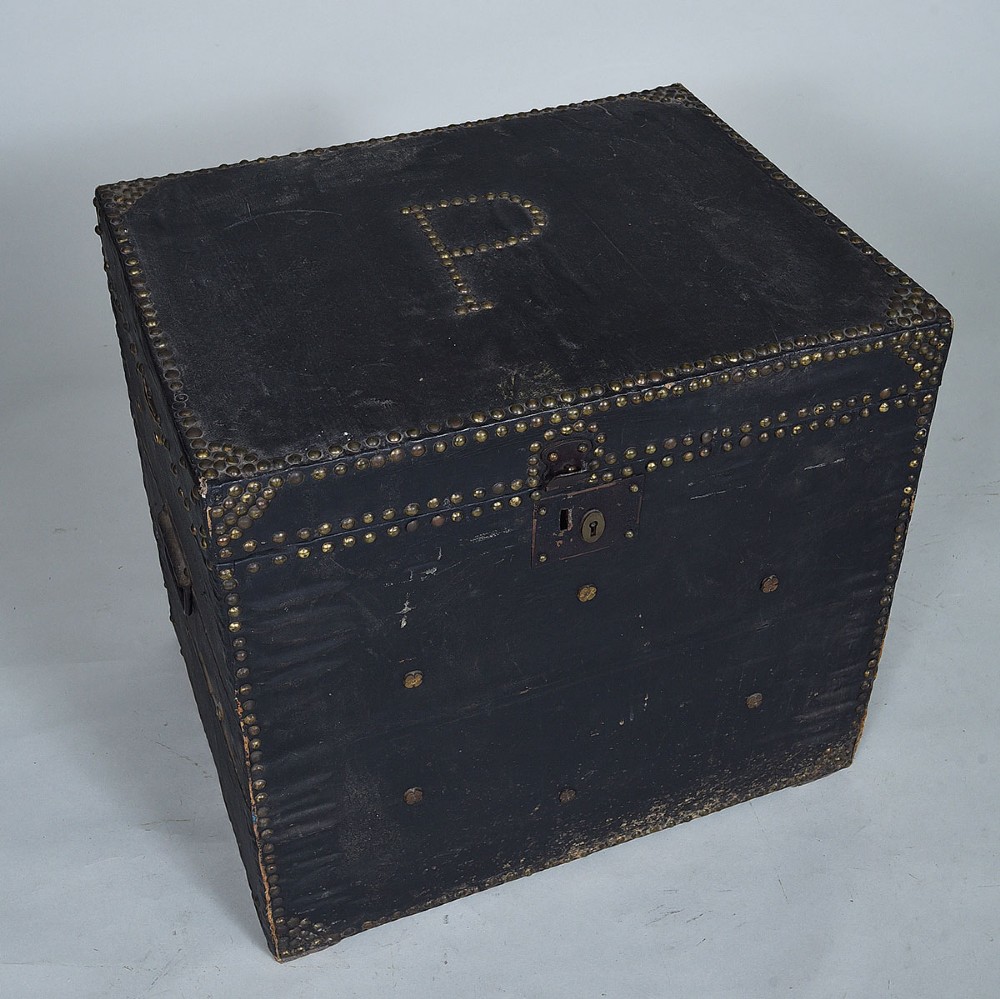 A dark leather-covered antique trunk featuring dense brass stud embellishments, a monogrammed lid, and a central brass lock plate. View II